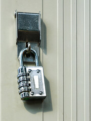 Close-Up of a Metal Combination Padlock Securing a Beige Vertical Panel Door in Daylight