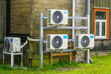 Multiple Air-to-Air Heat Pump Outdoor Units Installed on Wooden Wall of a Residential Building