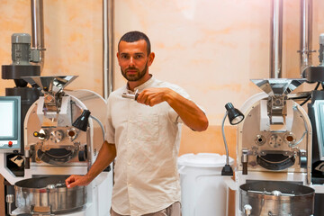 A skilled worker conducts coffee bean roasting in a workshop, focusing on arabica and robusta samples. The setup features advanced roasting machines designed for precise preparation