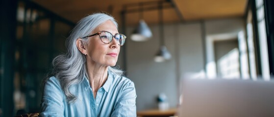 The thoughtful elderly woman enjoying a moment of reflection at her modern workspace.