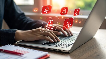 Photo of a person types on a laptop, with red notification bell icons appearing on the screen