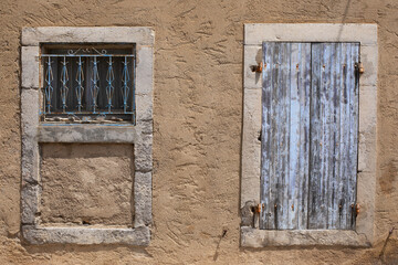 Vieux bâtiment en torchis beige et vielles pierres aux fenêtres délabrées et volets bleus lavande décrépit d'une maison abandonnée.