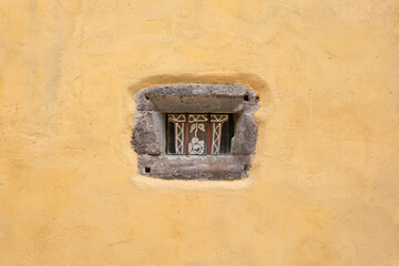 Petite fenêtre à barreaux, lucarne bordée de bloc de pierres d'une ancienne maison du Sud aux...