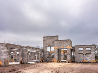 Street view of the concrete shell of a single-family house and attached garage under construction in a suburban residential development on an overcast winter afternoon in southwest Florida