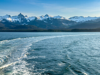 Curving wake of a small cruise ship along Favorite Channel, part of the Inside Passage, on a June evening in southeast Alaska. Motifs of travel and the recent past, navigation and changing course.