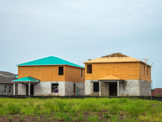 Rear view of two similar bi-level single-family houses under construction in a planned suburban community on an overcast morning in southwest Florida