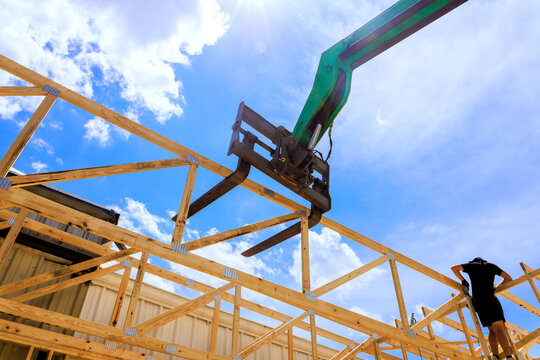 Worker positions wooden beams telehandler using machinery on construction site location