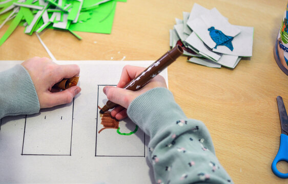 Konzept Kunst und Kreativit&auml;t Kinder: Blick auf einen Tisch, wo ein M&auml;dchen bunte Bilder ausmalt und dann ausschneidet.