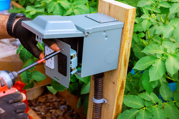 Electrician is working on installing an electrical USB ports outlet in garden to enhance...