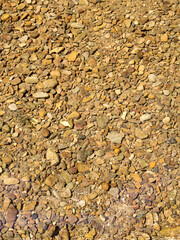 On the riverbed, countless rounded stones are visible, forming a mosaic relief beneath the...