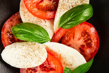Caprese salad mozzarella and tomato, basil fresh delicious gourmet food background on the table...