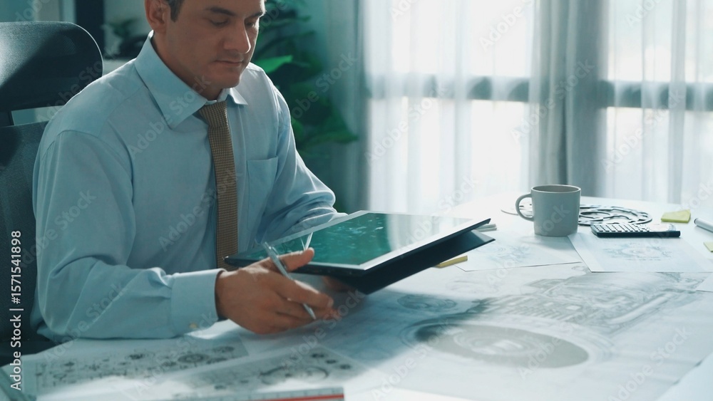 Poster professional engineer looking at phone while working on tablet with green screen at meeting table wi