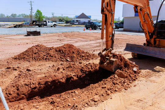 Excavator works on construction site creating trench while trucks are parked nearby during works area