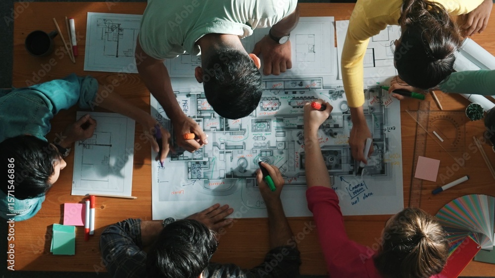 Poster top down view of civil engineer team writing at blueprint at meeting table with color palettes. grou