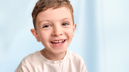 A cheerful guy with light brown hair smiles broadly, pointing at something, wearing a pastel...
