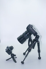 Photography equipment displayed against a plain background showcasing a large camera on a tripod and a small camera set up nearby
