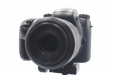 Professional DSLR camera with large lens positioned on a tripod against a white background