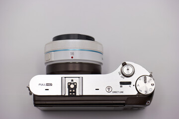 Camera with modern design showcasing control settings and lens details on a neutral background