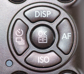 Camera control button layout featuring key functions like display, autofocus, and ISO settings for photography enthusiasts