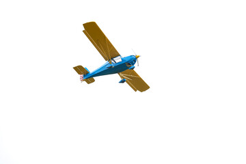 Isolated blue and yellow sport airplane flying against clean white background. Conceptual aviation...