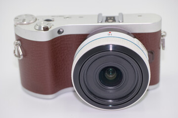 Compact camera with a stylish design featuring a brown leather grip and wide angle lens on a clean...