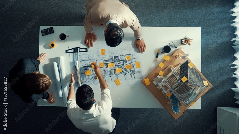 Poster top down view of architect engineer writing building structure idea on note and stick on blueprint. 