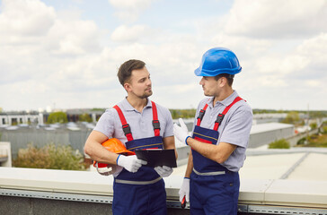 Group of builders discusses planning and strategy for construction while on a roof. The team...