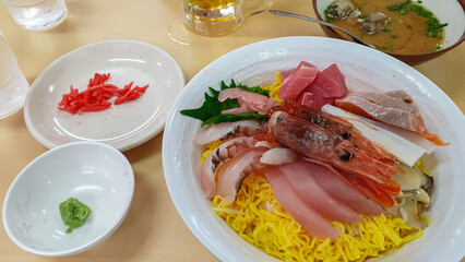 A colorful Kaisen Don bowl is filled with fresh sashimi, including tuna and shrimp, over a bed of...