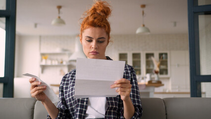Caucasian woman serious homeowner girl female at home couch reading letter paper notification debt trouble check payments bills analyze expenses budget money finances loan credit bank mortgage problem