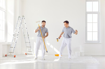 Two men, painters, dancing happily during the renovation of a house or apartment. Joy and camaraderie of a team working together on home renovation, happiness and teamwork amidst the work.