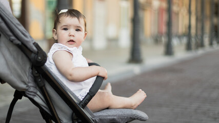Baby girl sitting in stroller looking away with blurred background