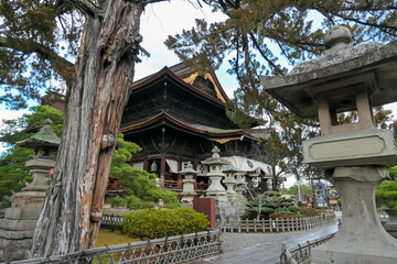 Intricate wooden architecture of Zenkoji Temple's main hall in Nagano, Japan, is framed by an...