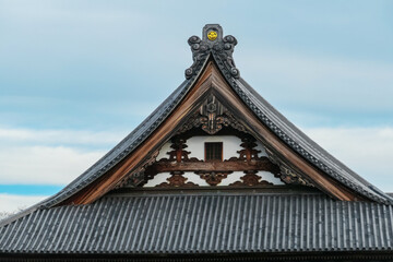 A close-up of an ornate temple gable (hafu) at Zenko-ji, showcasing intricate wooden carvings and...