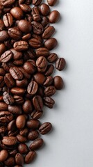 Naklejka premium Light gray background showcases scattered coffee beans, highlighting their rich textures and potential as a design element