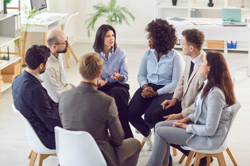 Group of multiracial company employees sitting together in circle during business meeting or...