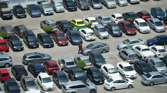 Many cars are parked in an outdoor parking lot on a sunny day