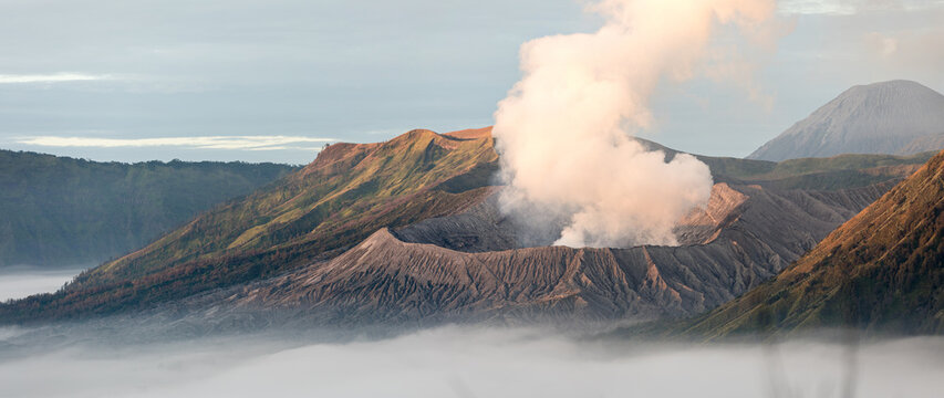 View of the majestic Mount Bromo volcano piercing through a sea of ethereal white clouds, its rugged landscape contrasting against the soft sky, Mount Bromo, East Java, Indonesia.
