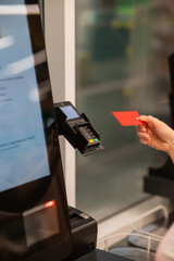 Woman paying with credit card at self-checkout. 