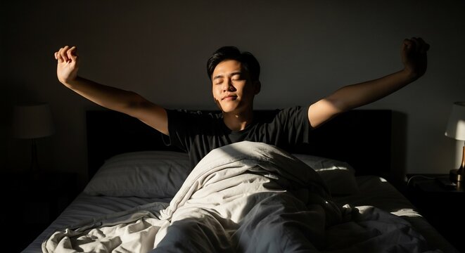 Young Man Stretching in Bed Bathed in Warm Morning Sunlight