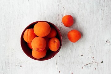 Ripe apricots in a bowl on a white wooden background