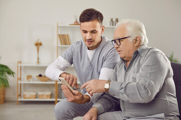 Mobile health tutorial. Healthcare professional instructs elderly man on using health app on mobile...