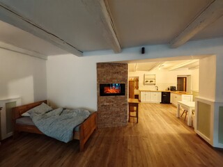 Rustic village-style hotel room interior featuring a crackling fireplace and wooden furniture.
