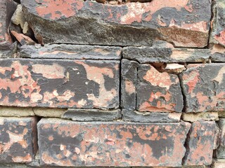 Cracked brick wall with blackened mortar lines for rustic architectural textures and urban visuals