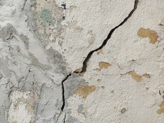 White painted wall with diagonal crack and peeling areas for distressed texture and real surface use