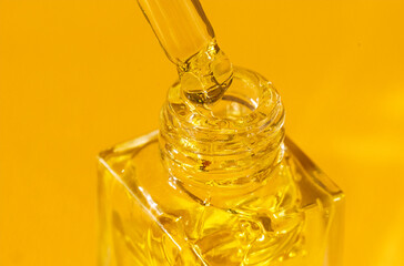 Close-up of a clear glass bottle with a moisturizing serum and a pipette in bright sunlight.