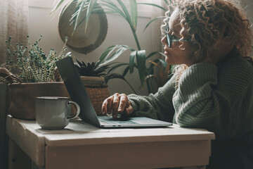 Curly-haired woman in her 40s using a laptop at home with varied expressions. Remote work, digital...