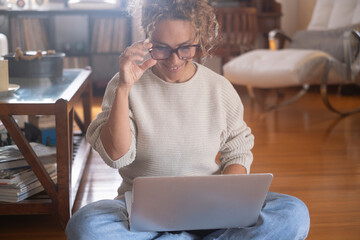 Curly-haired woman in her 40s using a laptop at home with varied expressions. Remote work, digital...
