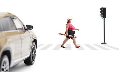 Corpulent woman crossing a street and carrying a beach umbrella
