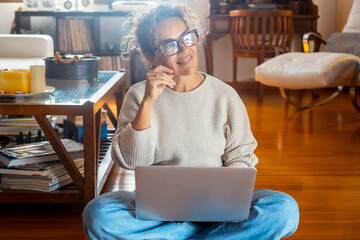 Curly-haired woman in her 40s using a laptop at home with varied expressions. Remote work, digital...