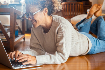 Curly-haired woman in her 40s using a laptop at home with varied expressions. Remote work, digital...